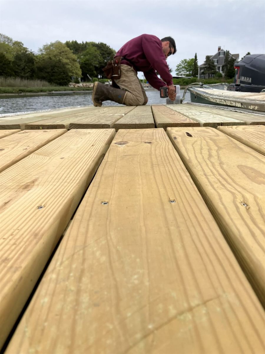 Connor Rogan installing fresh decking on a floating dock in Barnstable Harbor on Cape Cod